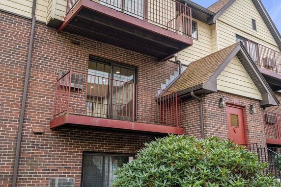 Front view of a multi-story brick building with balconies and a red door.