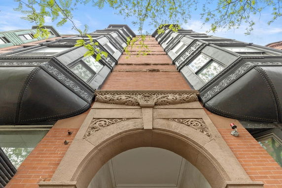 Front view of a multi-story brick building with ornate stonework and large windows.