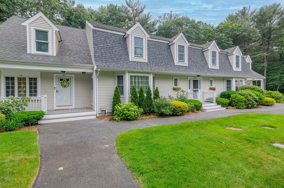 Front view of a two-story house with dormer windows and a landscaped pathway.
