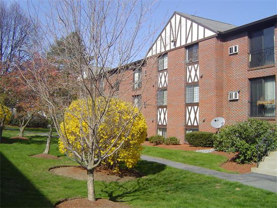 Front view of a multi-story brick apartment building with Tudor-style detailing.