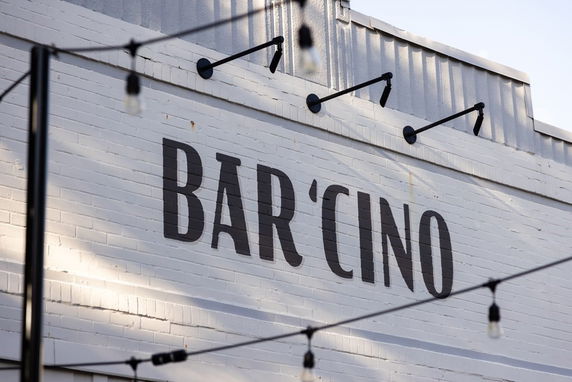 Front view of a building with 'BAR'CINO' sign on white brick wall.