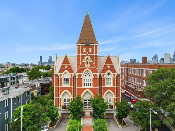 Front view of a large, red-brick building with pointed arches and a central tower.