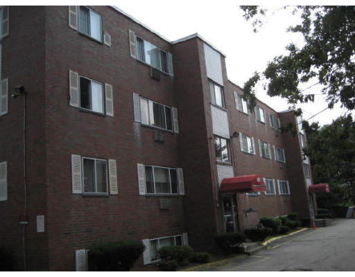 Front view of a multi-story brick apartment building with several windows and awnings.