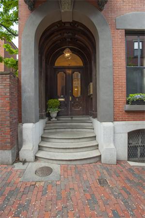 Front view of a brick building with an arched entrance and steps leading up to the door.