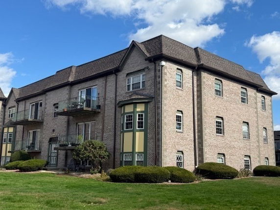 Front view of a two-story building with balconies and a complex roof design.