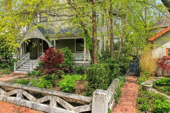 Front view of a two-story house with a porch and garden.