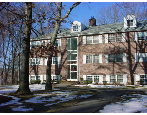 Front view of a multi-story brick building with a central glass entryway and dormer windows.
