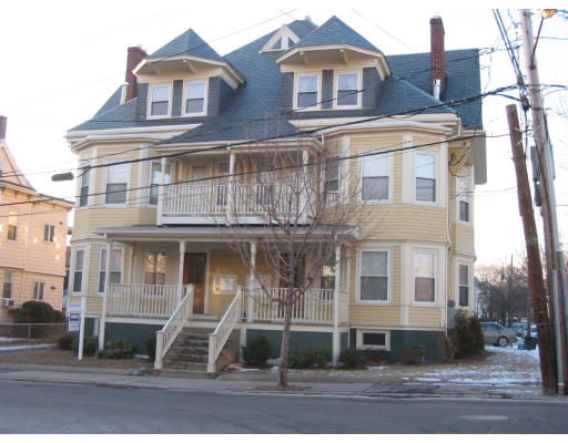 Front view of a multi-story house with a porch and multiple dormer windows.
