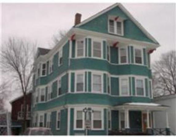 Front view of a multi-story residential building with a gable roof.