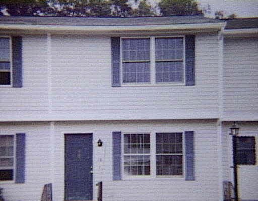 Front view of a two-story townhouse with blue shutters and a dark front door.