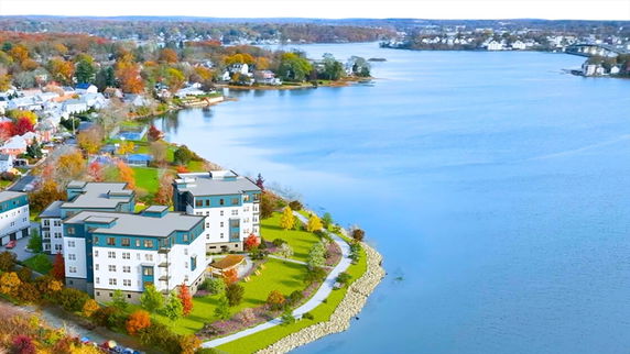Aerial view of a lakeside residential area with multiple buildings and surrounding landscape.