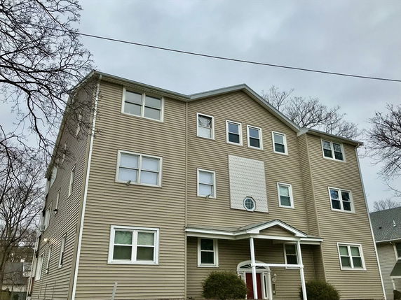 Front view of a multi-story residential building with beige siding and multiple windows.