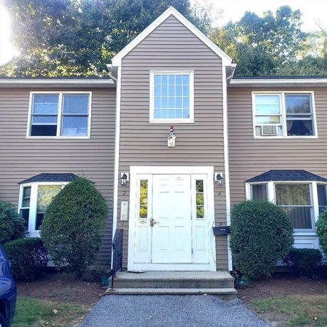 Front view of a two-story house with a central peaked section and symmetrical windows.
