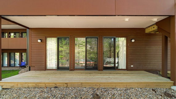 Front view of a house with large glass doors and a wooden deck.
