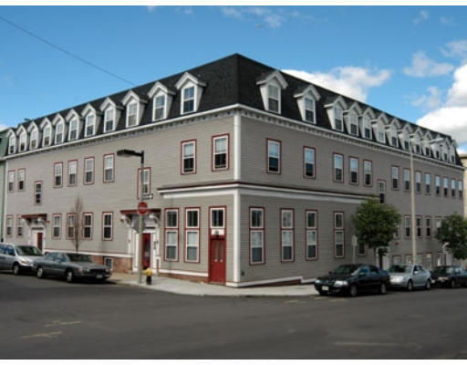 Front view of a multi-story building with a mansard roof and numerous windows.