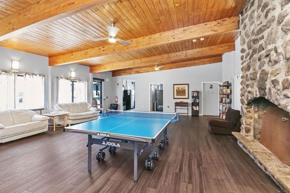 Recreational room with ping pong table, sofas, and stone fireplace.