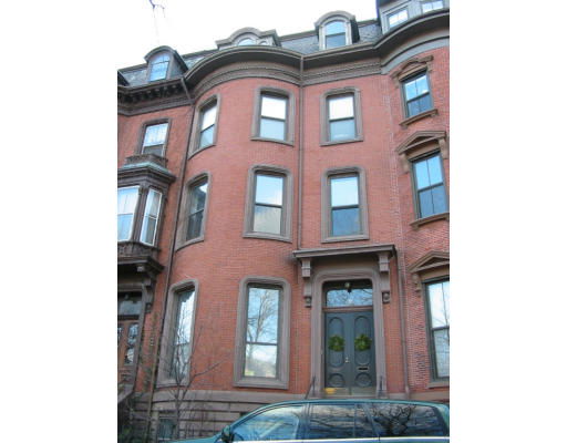 Front view of a multi-story brick building with tall windows and decorative trim.