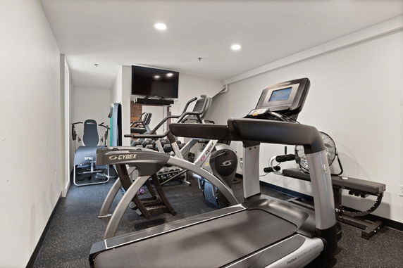 Indoor gym area equipped with exercise machines and a television.