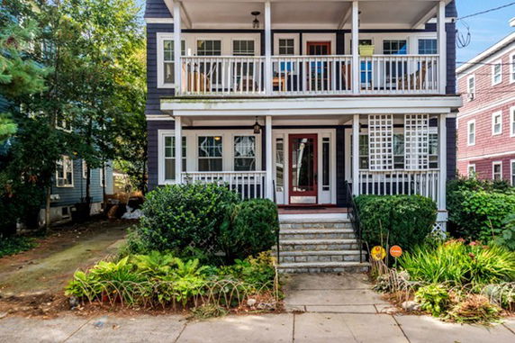 Front view of a two-story house with balconies and a garden.