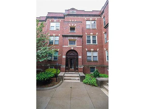 Front view of a multi-story brick apartment building with a central entrance.