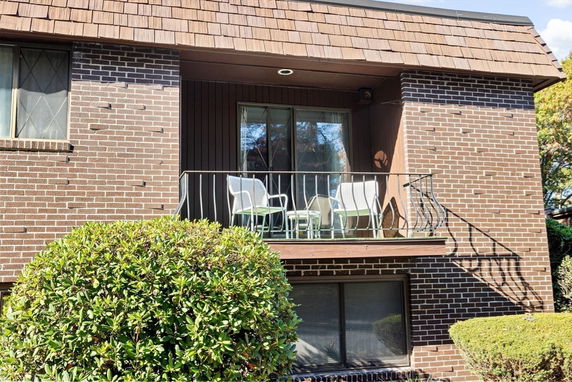 Front view of a two-story house with a balcony and brick exterior.