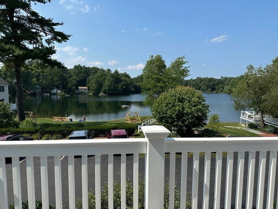 Panoramic view of a lake and surrounding greenery from a building balcony.