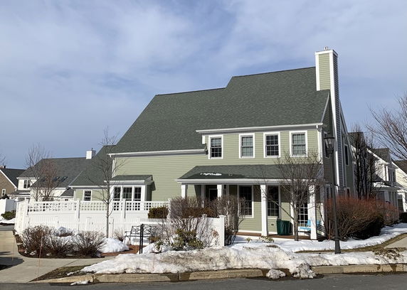 Front view of a two-story house with a green facade and white trim.