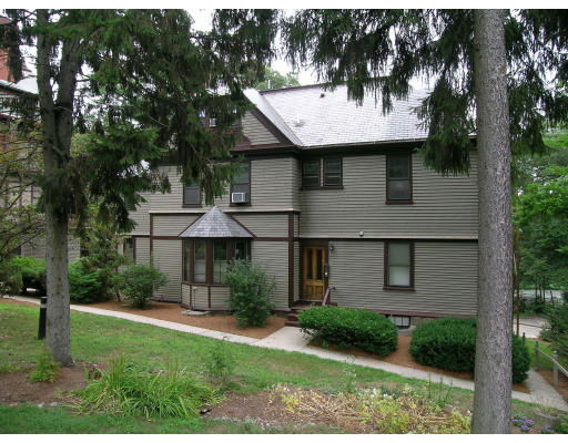 Front view of a two-story house with a porch and brown siding.