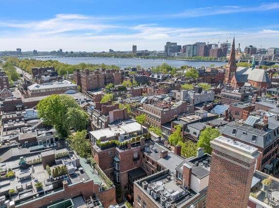 Panoramic view of urban buildings overlooking a river and distant skyline.