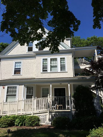 Front view of a multi-story house with a porch and railing.