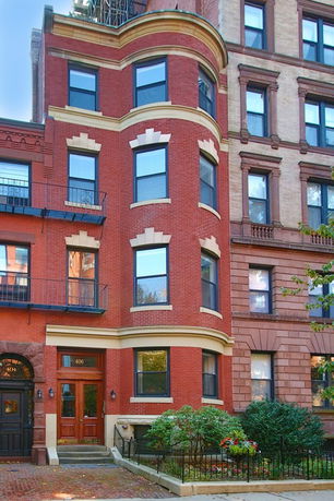 Front view of a multi-story brick building with bay windows and decorative trim.