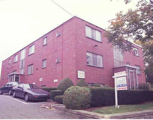 Front view of a two-story brick building with multiple windows and a parking area.
