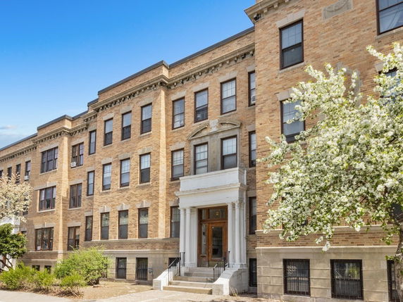 Front view of a multi-story brick apartment building with decorative entrance.