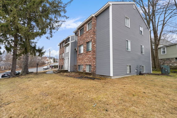 Side view of a multi-story residential building with brick and siding exterior.