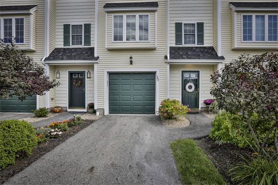 Front view of a two-story townhouse with a single-car garage and two entrances.