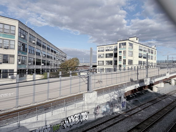 Front view of a multi-story industrial building near train tracks.