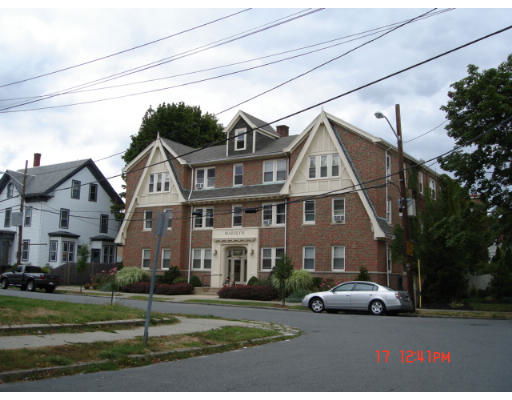 Front view of a multi-story brick building with a complex roof design and dormer windows.