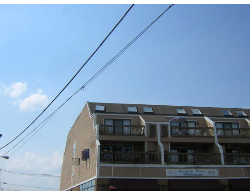 Front view of a multi-story building with balconies and a sloped roof.