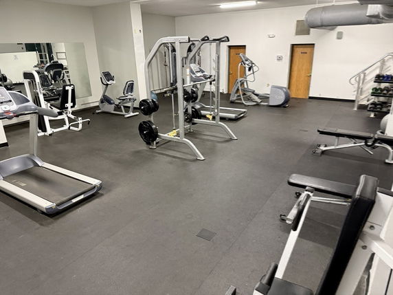 Interior view of a gym area with exercise equipment including treadmills and weight machines.