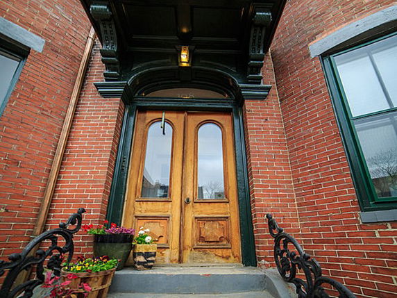 Front view of a brick building entrance with wooden double doors and decorative molding.