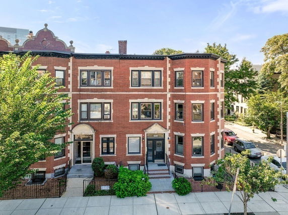 Front view of a three-story brick apartment building with multiple windows.