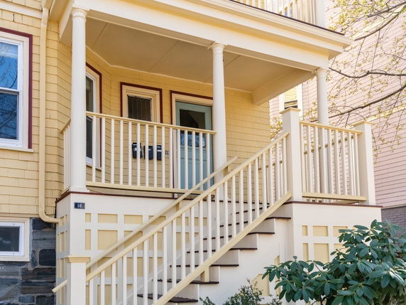 Front view of a two-story house with a porch and stairs.