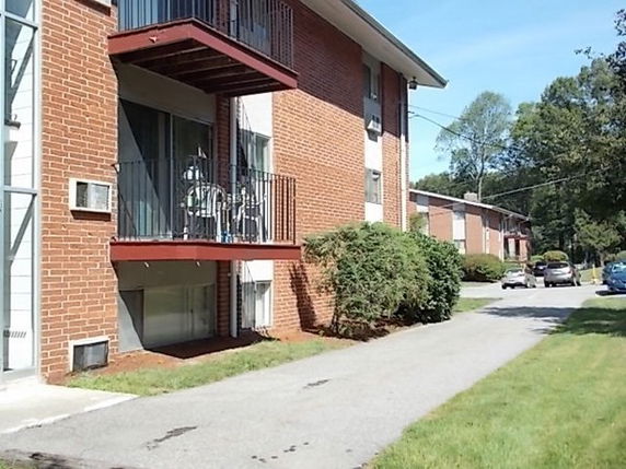 Front view of a multi-story brick apartment building with balconies.