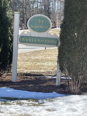 Sign for Overland Park at 135 Broad Street surrounded by trees and snow.