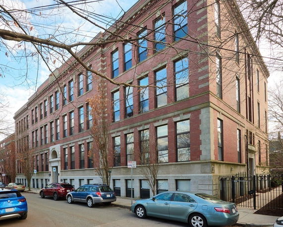 Front view of a multi-story brick building with large windows.