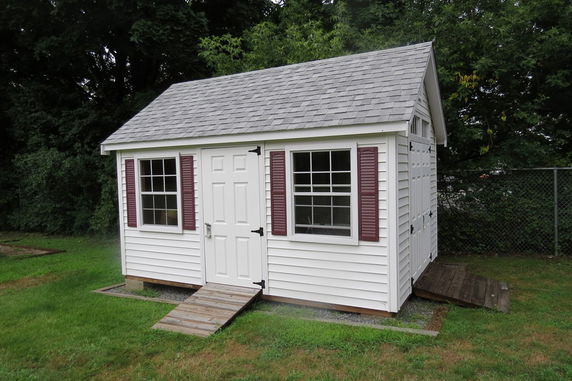 Front view of a small white shed with a gable roof and two windows.