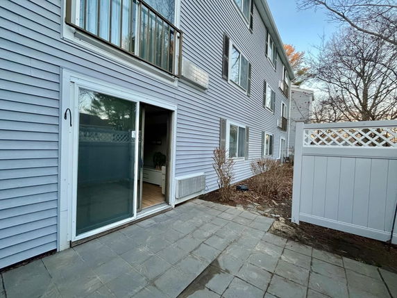 Exterior view of a multi-story building with sliding glass door and adjacent balcony.