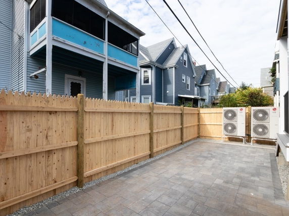 Outdoor area with fenced boundary and multiple houses in the background.