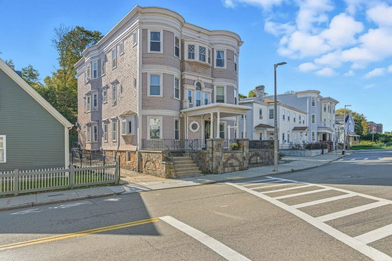 Front view of a multi-story building with bay windows and a porch.