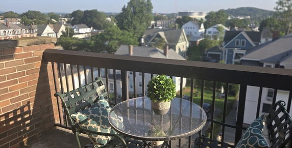 View of surrounding residential area from a balcony with outdoor seating.